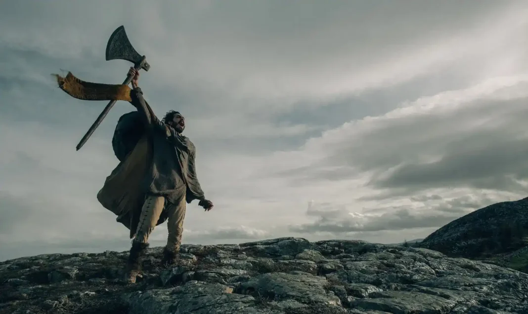 Fotograma de El caballero verde (The Green Knight, 2021), de David Lowery; en el que el protagonista alza sobre su cabeza un hacha
